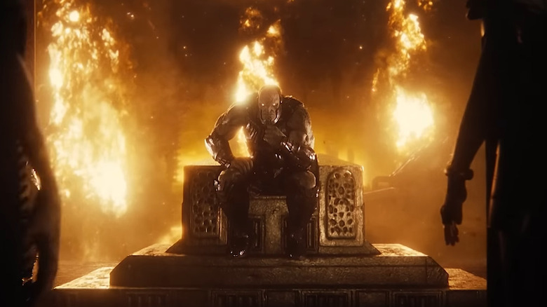 Darkseid sits on a throne, beset by fire