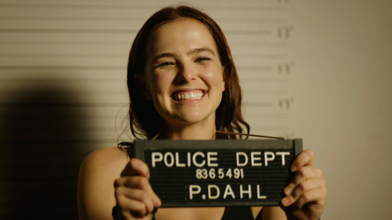 Zoey Deutch having her picture taken in prison in "Buffaloed"